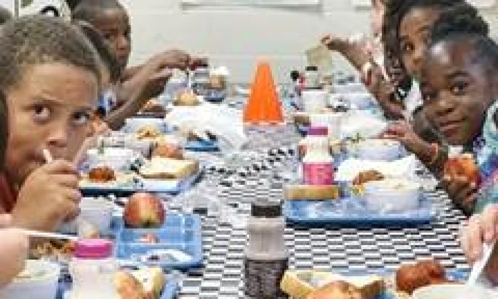 Kids sit at cafeteria table eating