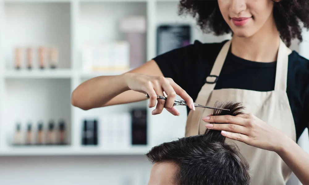 Hair stylist in salon cutting male customer's hair