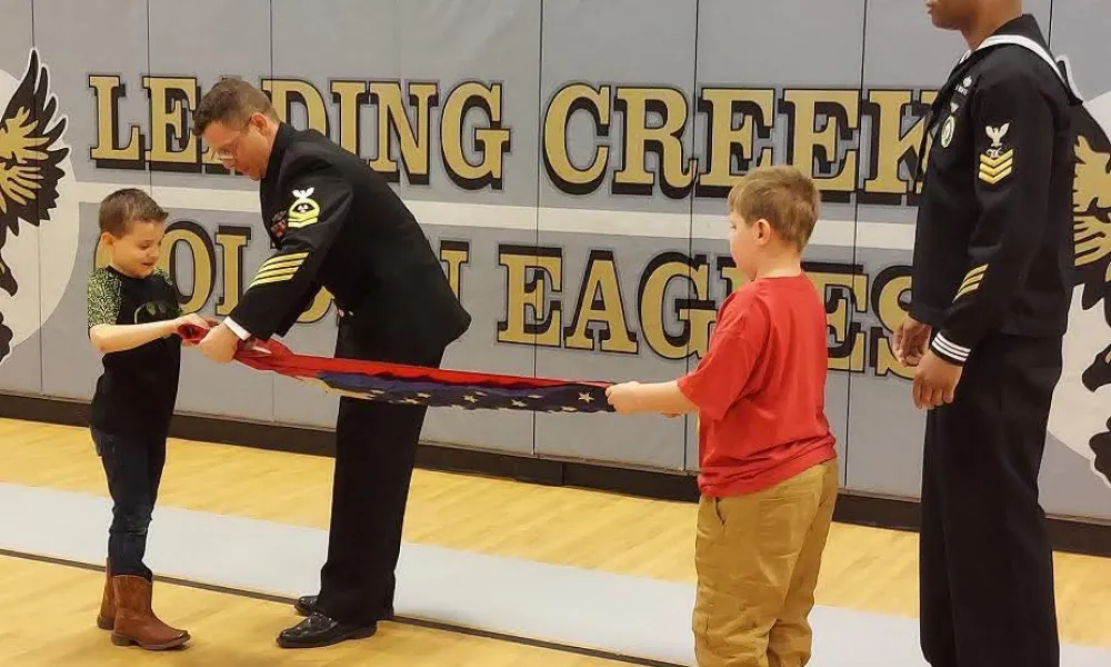 Children learning to fold a flag at a speaker series event.
