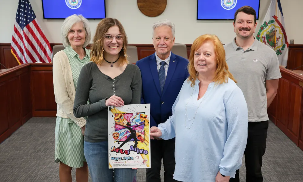 2025 Arts Alive poster contest winner posing with the winning poster with staff from the WV Department of Education