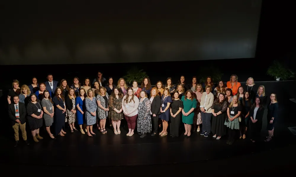 National Board Certification honorees standing together on stage at 2025 celebration