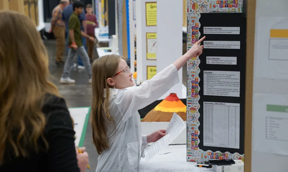 Female student pointing at her science project.