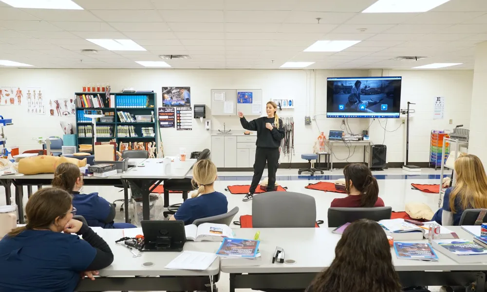 A woman teaching nursing students front the front of the classroom.