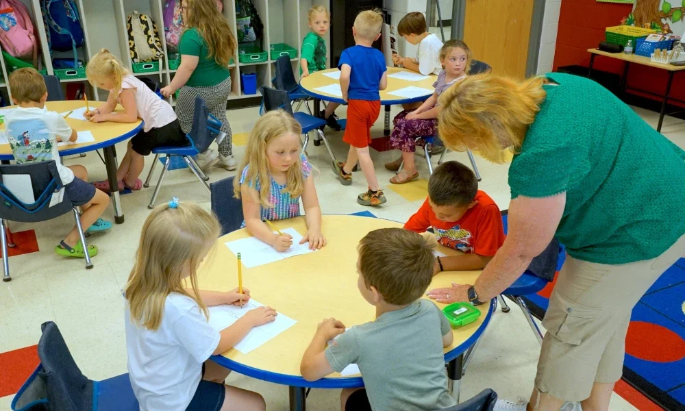 A woman assisting children with a classroom activity.