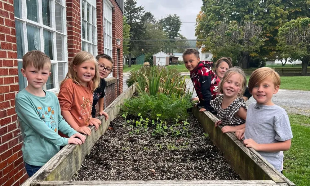 Students standing around a bed of soil for a Farm to School project.