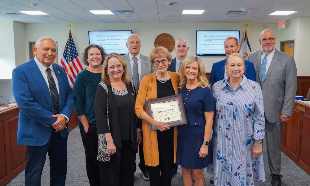 West Virginia Board of Education members surrounding Debra Sullivan. She is holding a frame.