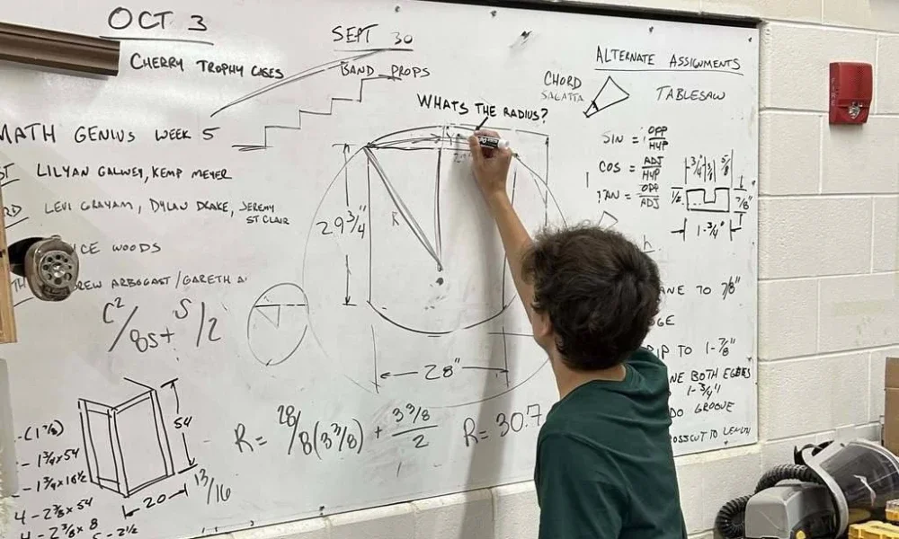 A student solving math equations on a whiteboard.