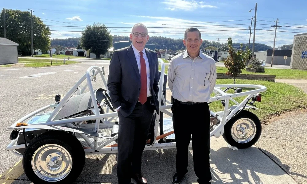 two people standing in front of a vehicle.
