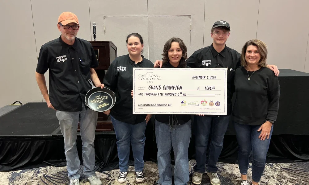 A group of people holding a price check for being named grand champion
