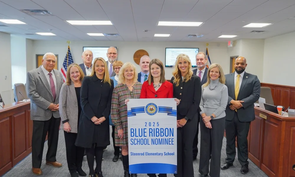 A group of people gathered around a banner with the words "2025 Blue Ribbon School Nominee Steenrod Elementary School" on it.