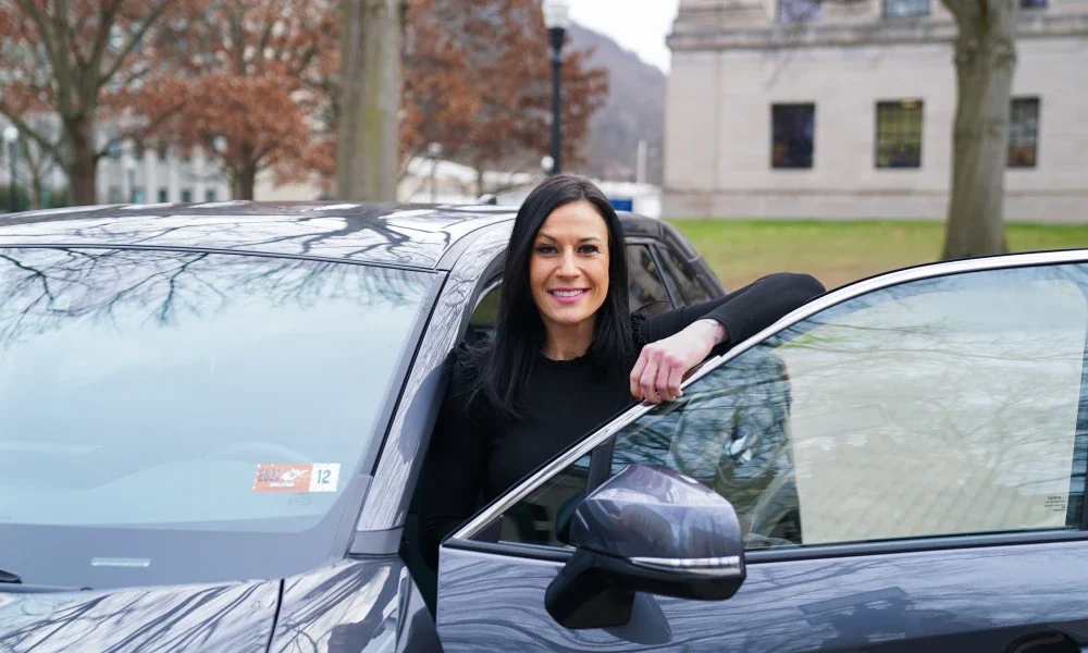 Tiffany Stephen smiling while standing behind a car door.