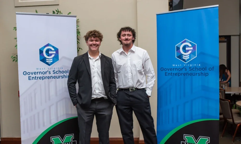 Two people standing in front of Governor's School of Entrepreneurship banners.