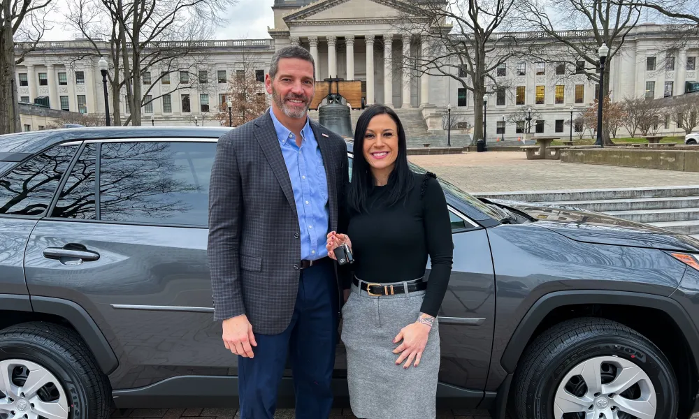 David Rosier and Tiffany Barnes smiling while standing in front of a Toyota RAV4.