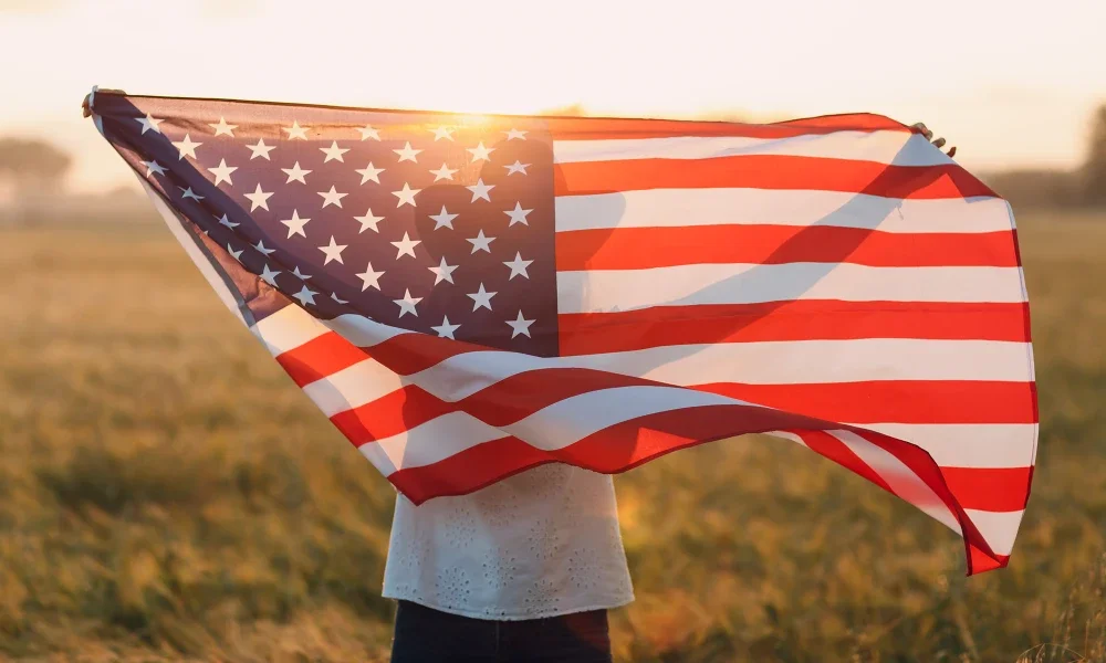 Woman holding American flag in a grassy field