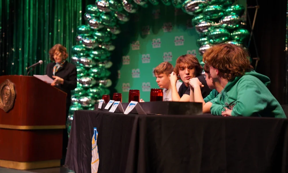 Students sitting at a table talking to one another.
