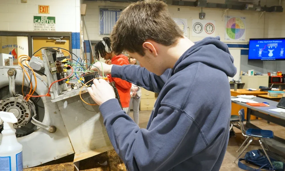 A student working with the wiring of an HVAC unit.