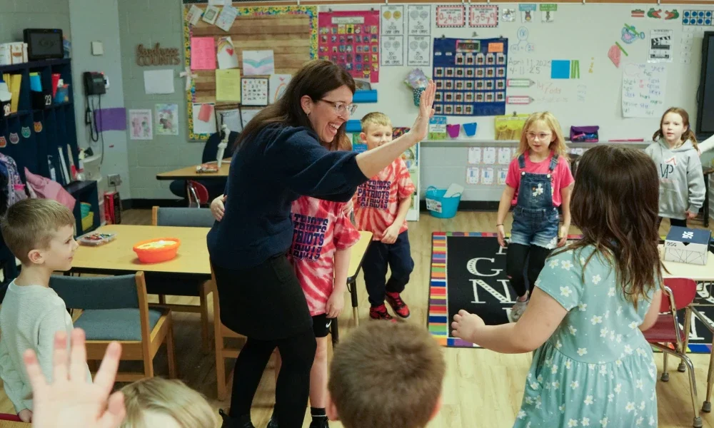 A principal giving a student a high five in a classroom.