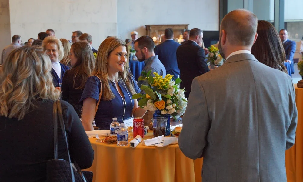 People standing at a table enjoying refreshments, talking, and laughing