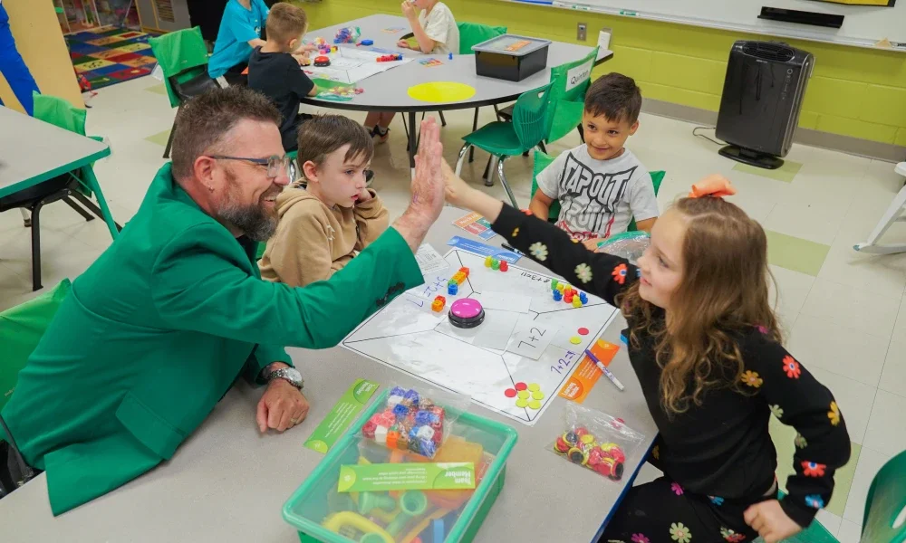 Justin Endicott giving a student a high five while other students watch.