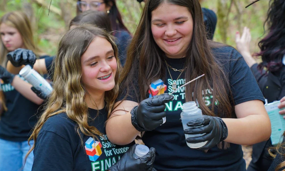 Two students smiling while looking at a bottle of water. 