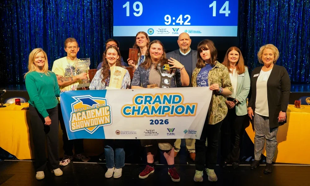 Members of Morgantown High School's Academic Showdown team smiling while holding a banner and a trophy. 
