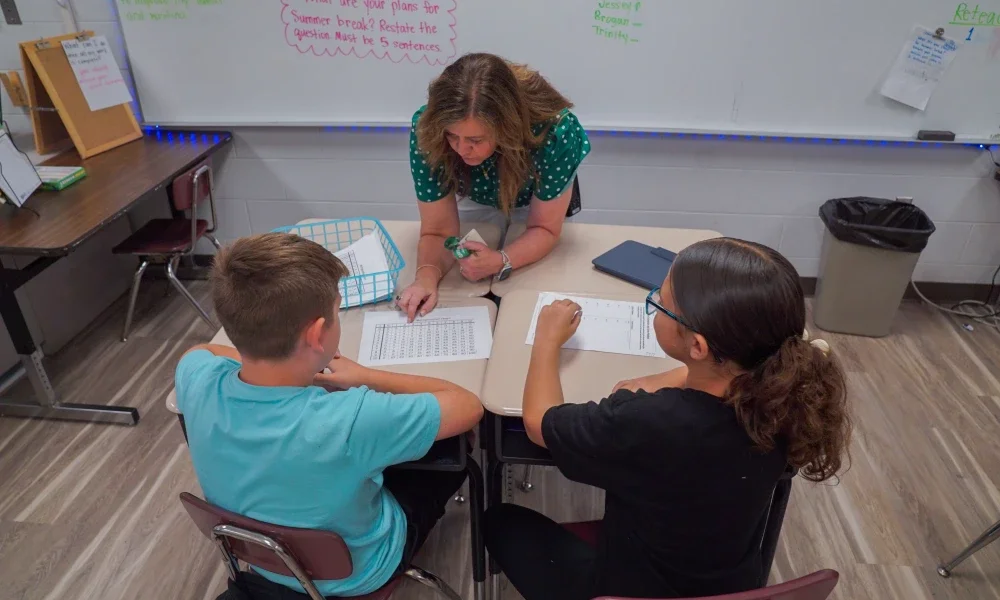 An adult helping students with their work. 