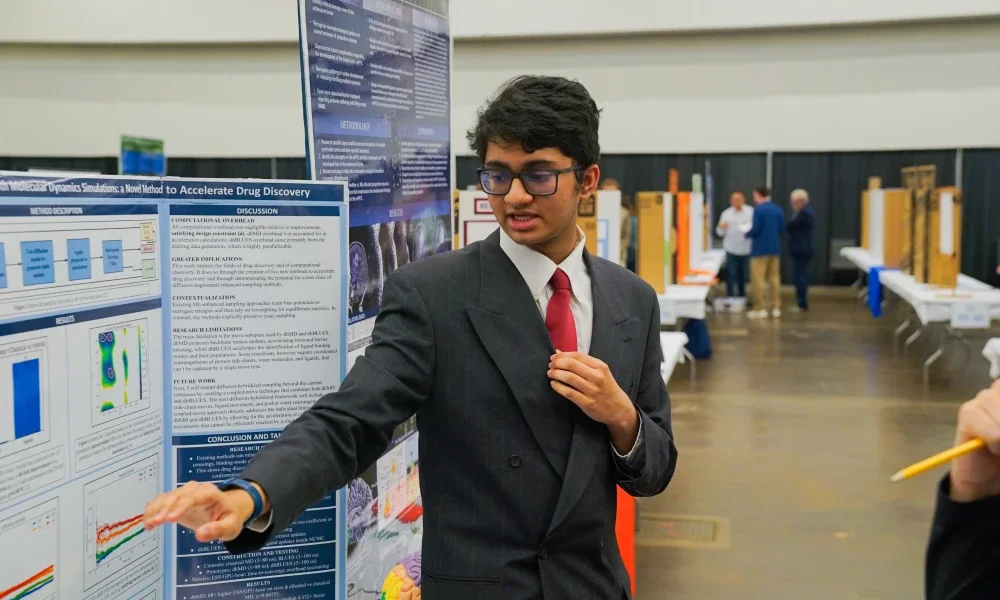 A student pointing toward his science project. 