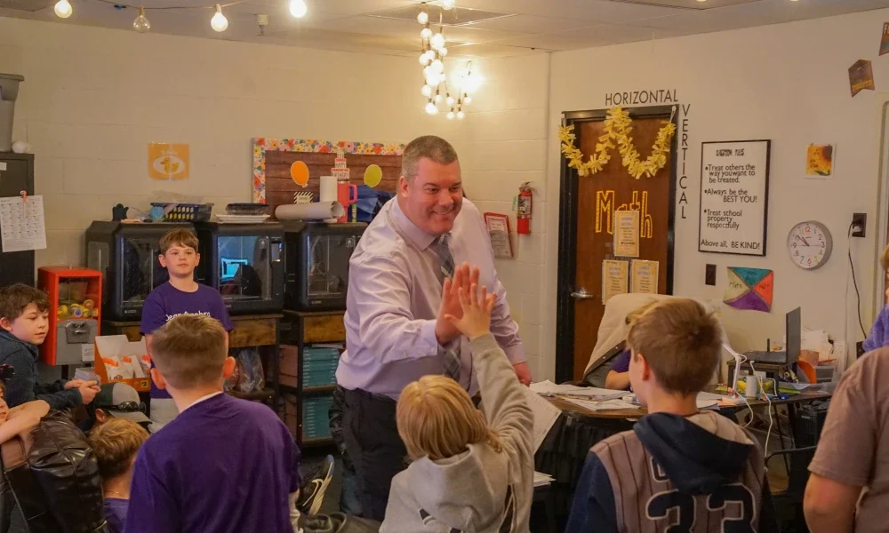 A school principal giving a student a high-five. 