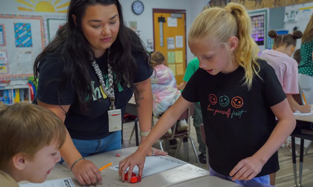 A teacher helping students in a classroom. 