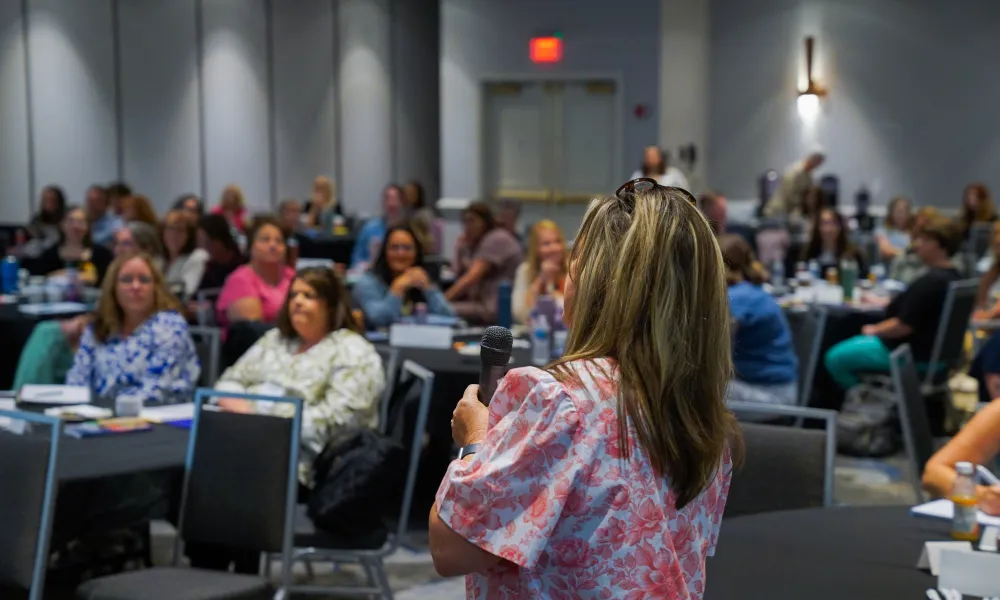 Kelly Griffith speaking to an audience while holding a microphone. 