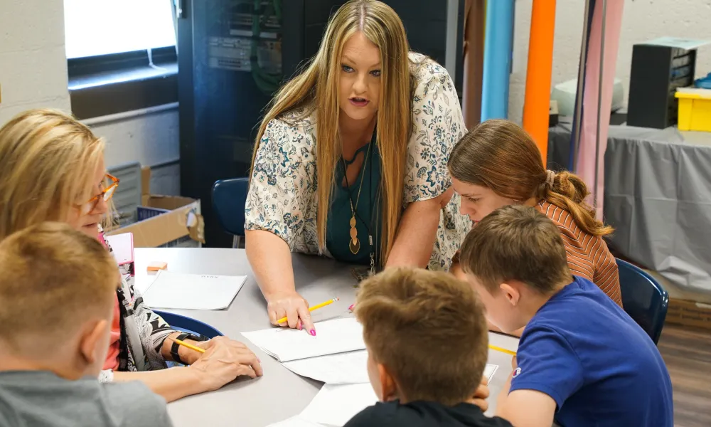 A teacher works with students on classwork