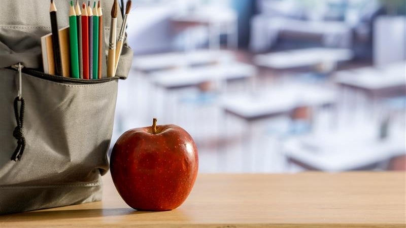 An apple sits on top of a teacher's desk.