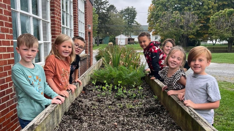 Students standing around a bed of soil for a Farm to School project.