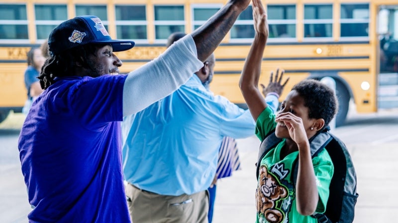 An adult giving a student a high five.