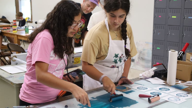 Two female students preparing ink for use in a printmaking exercise in a art room.