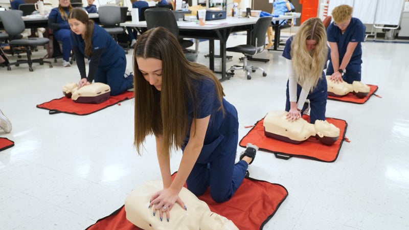 Students practicing CPR on a test dummy.