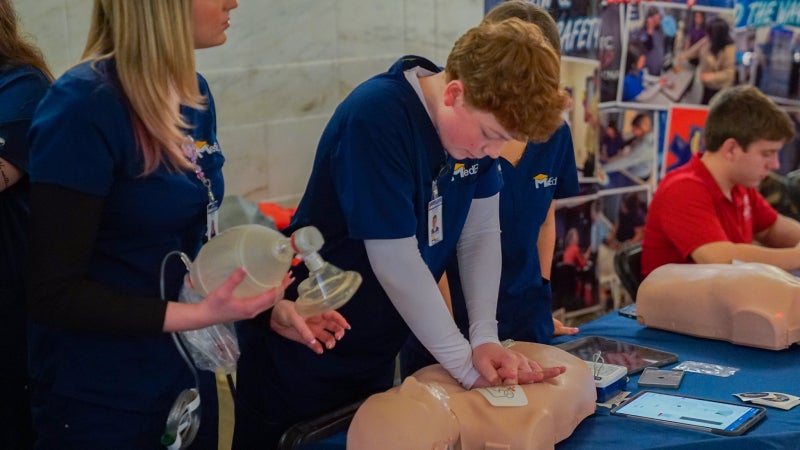 A student practicing CPR on a practice dummy.