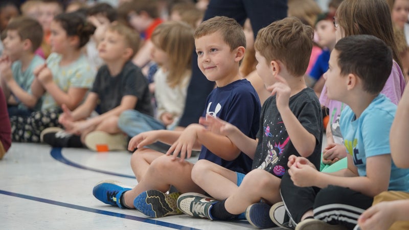 Students sitting on the floor and smiling