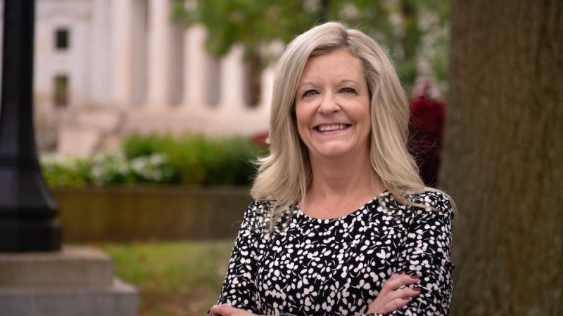 Michele Blatt leaning against a tree while smiling. 