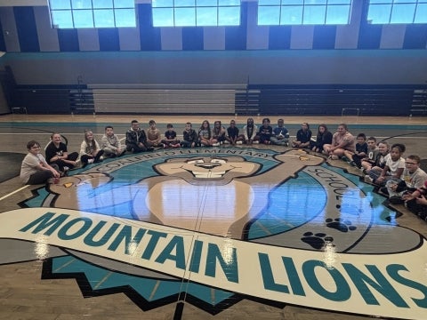 Students sitting on their school gymnasium floor. Mountain Lions.