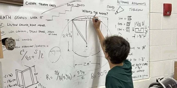 A student solving math equations on a whiteboard.