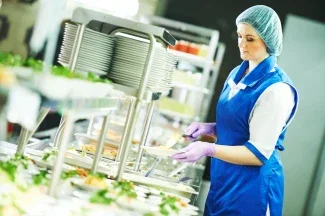 buffet female worker preparing and servicing food in cafeteria