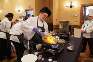 A student cooking something in a pan.