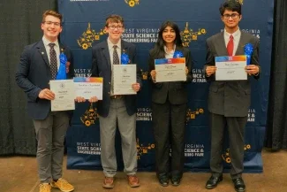 Joseph Nodurft, Jaxon Milam, Iqraa Zaman and Pavan Subramani smiling while holding certificates..