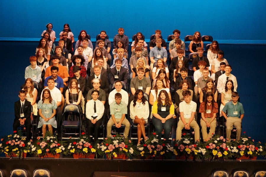 A group of students sitting in chairs on a stage.