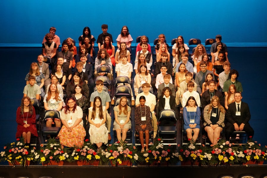 A group of students sitting in chairs on a stage.