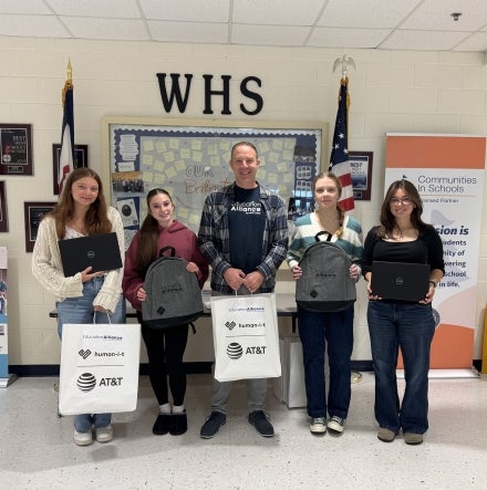 Five people holding bags and smiling.