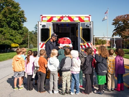 Students standing behind an ambulance listening to a first responder give a lesson.