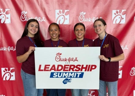 Students holding a sign that says "Chick-fil-A Leadership Summit."