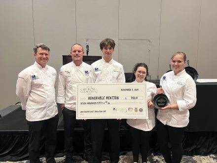 A group of people holding a prize check for being named an honorable mention.